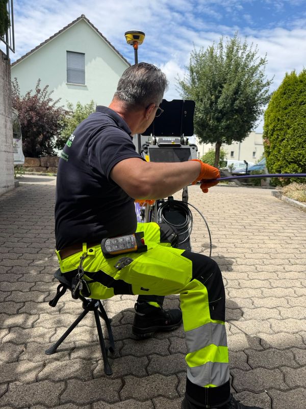 Greentech-Techniker führt das Kamera-Schubkabel mit Schutzhandschuhen in die Leitung