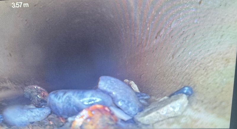 TV-Kamera-Aufnahme aus einer Abwasserleitung: Geröll und Ablagerungen auf der Rohrsohle, Zählerstand 3.57 Meter